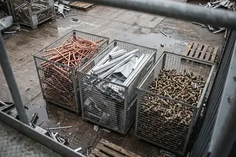 Drei Gitterboxen von schräg oben, sortenrein gefüllt mit Kupferrohren, Aluminiumprofilen und Messing-Fittings